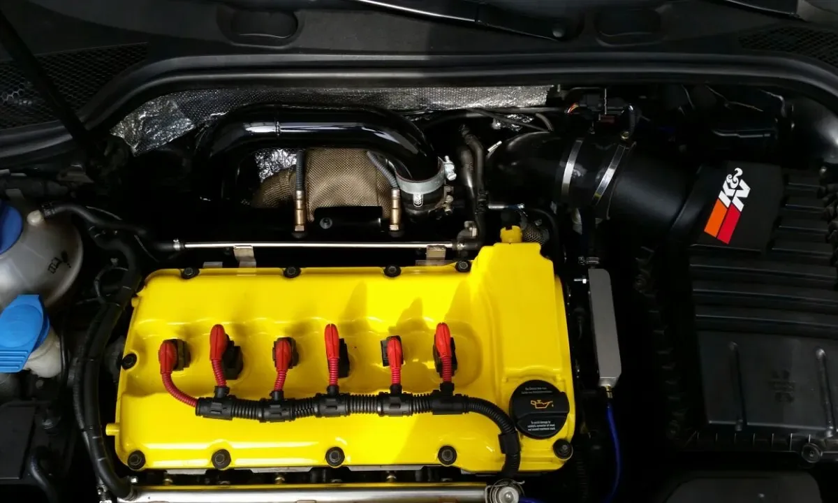 Motorraum des Audi A3 R30 Turbo mit gelb lackiertem Ventildeckel, roten Zündspulen und K&N-Ansaugung