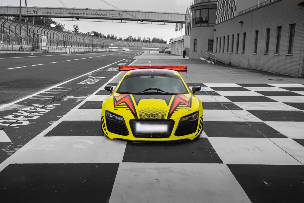 Audi R8 V10 Plus mit Heckflügel frontal auf schwarz-weiß kariertem Boden in der Boxengasse