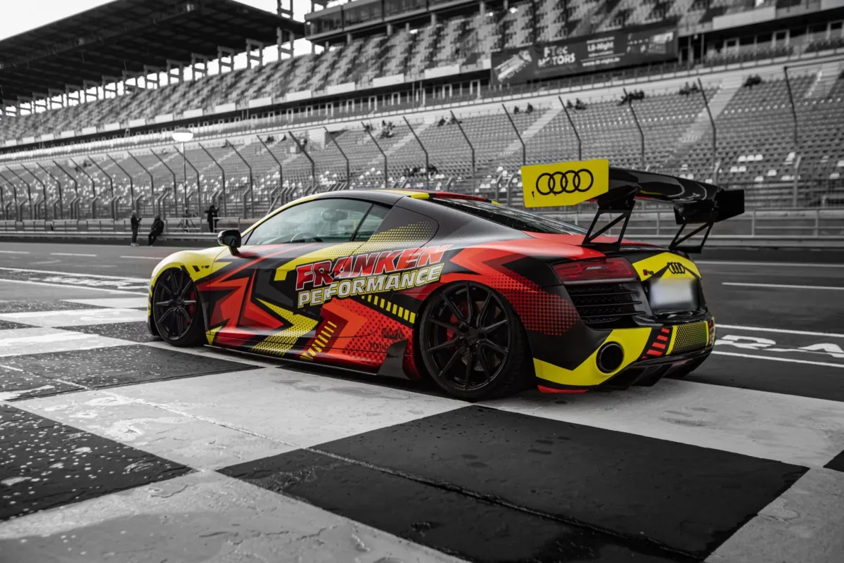 Audi R8 V10 Plus mit großem Heckflügel und Digitaldruck-Folierung, schräg von hinten in der Boxengasse