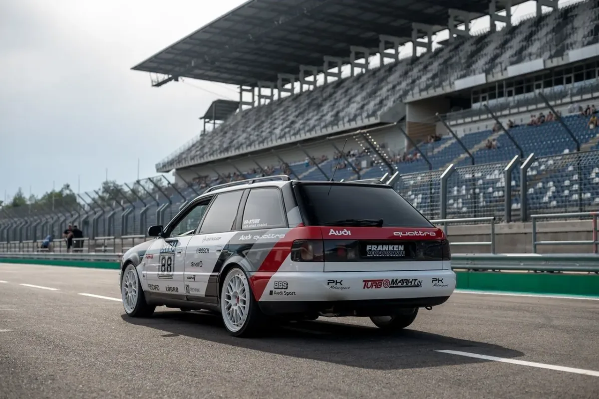 Audi S6 C4 Avant mit Motorsport-Folierung in der Boxengasse, schräg von hinten vor der Tribüne