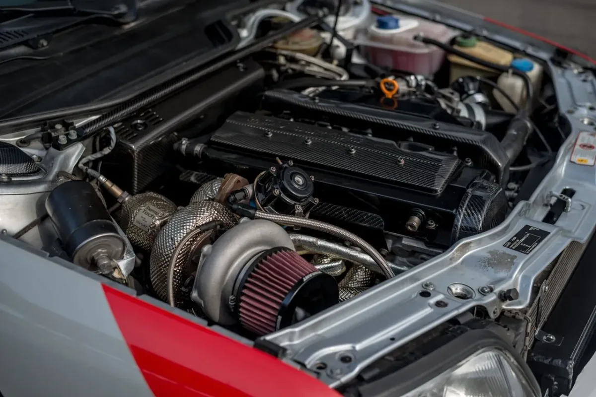 Motorraum des Audi S6 C4 20VT mit Turbolader, thermoisoliertem Krümmer, offenem Luftfilter und Carbon-Abdeckungen