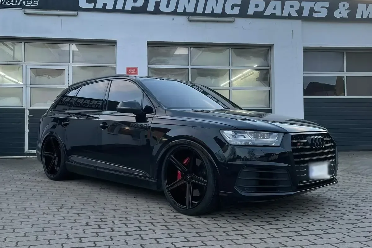 Audi SQ7 4M in Schwarz mit MB-Design-Felgen vor der Werkstatt mit dem Schild „Chiptuning Parts & More“ unter Abendhimmel