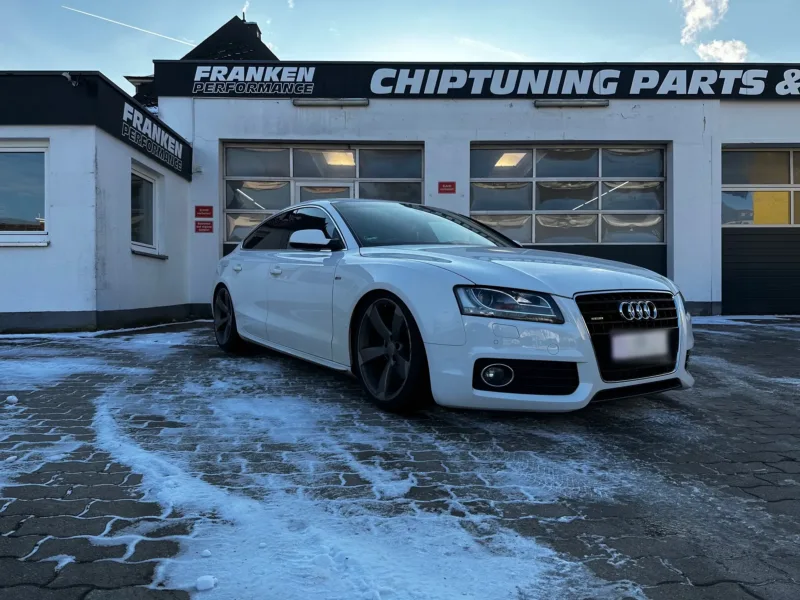 Weißer Audi A5 Sportback mit dunklen Felgen im Rotor-Design im Schnee vor der Werkstatt von Franken Performance