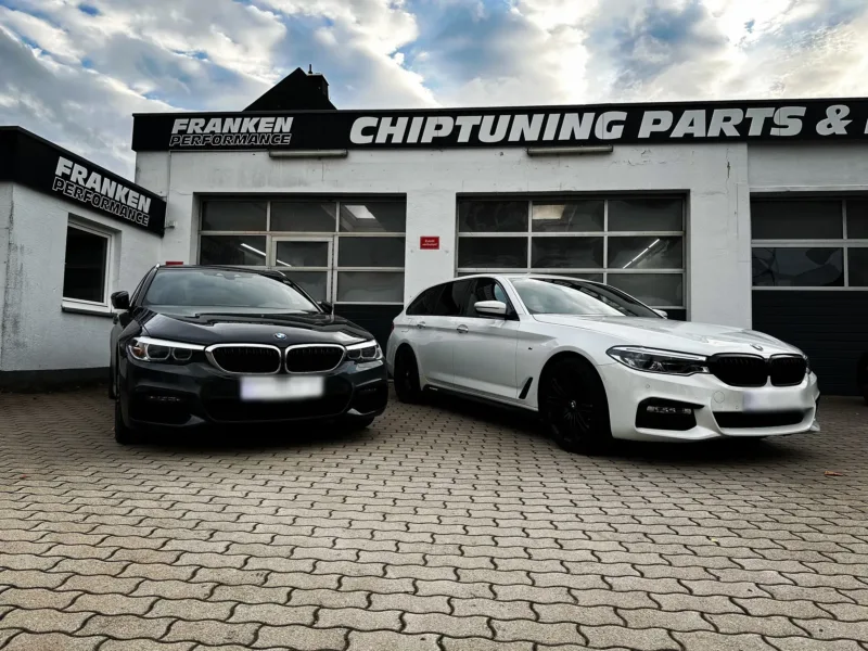Zwei BMW 5er in Schwarz und Weiß nebeneinander vor der Werkstatt von Franken Performance