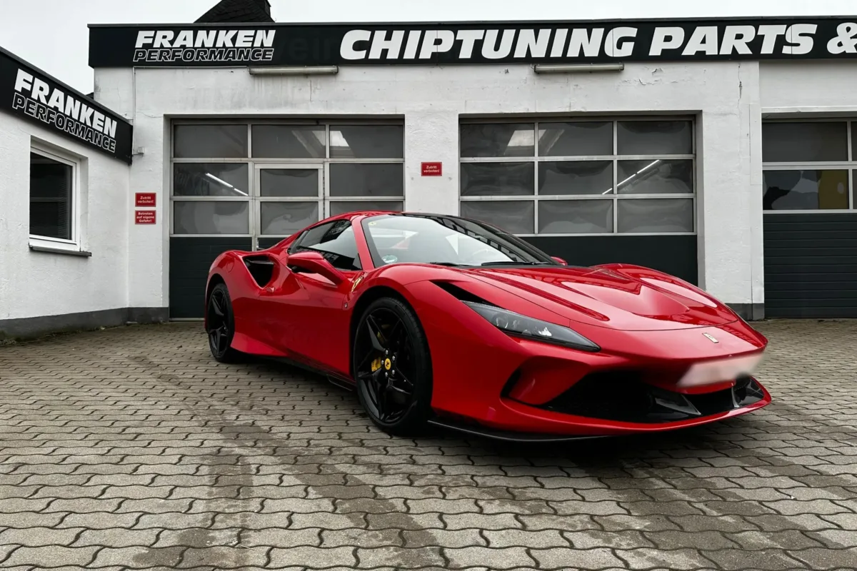 Roter Ferrari F8 Spider vor der weißen Werkstatt von Franken Performance mit dem Firmenschild „Chiptuning Parts“ über den Hallentoren