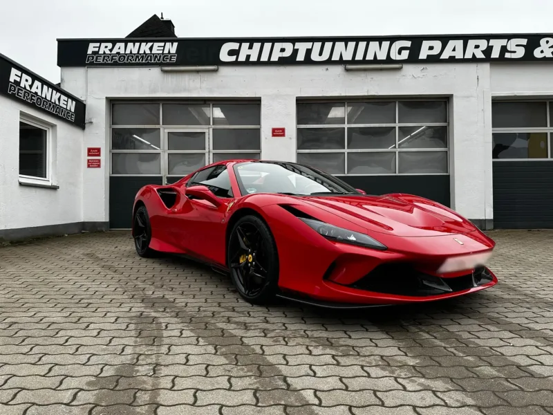 Roter Ferrari F8 Spider vor der weißen Werkstatt von Franken Performance mit dem Firmenschild „Chiptuning Parts“ über den Hallentoren