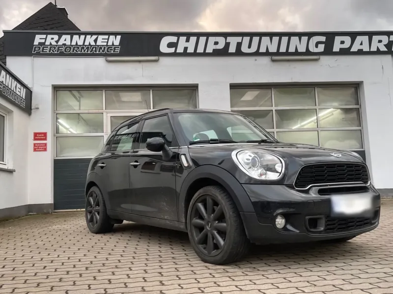 Dunkelgrauer MINI Countryman mit schwarzen Felgen vor der Werkstatt von Franken Performance