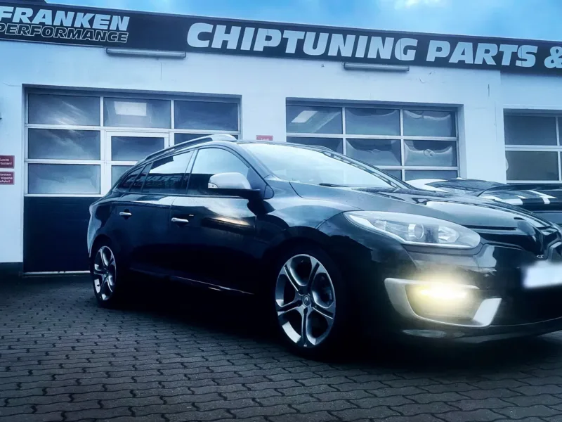 Schwarzer Renault Mégane Grandtour GT mit eingeschalteten LED-Tagfahrlichtern vor der Werkstatt von Franken Performance