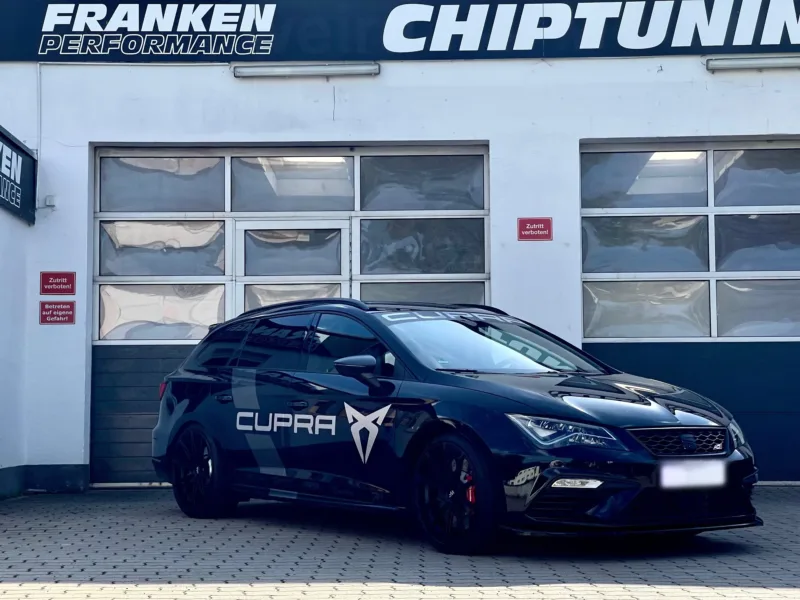 Dunkelblauer Seat Leon ST Cupra mit Cupra-Folierung und schwarzen Felgen vor der Werkstatt von Franken Performance