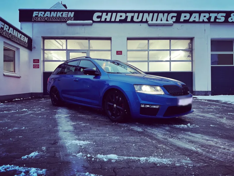 Blauer Škoda Octavia RS Combi mit schwarzen Felgen im Schnee vor der Werkstatt von Franken Performance