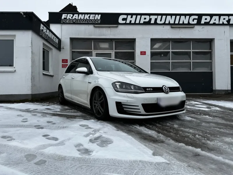 Weißer VW Golf 7 GTD im Schnee, Frontansicht vor der Werkstatt von Franken Performance