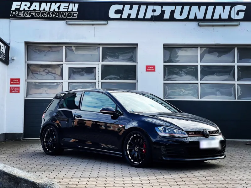 Schwarzer VW Golf 7 GTI mit schwarzen Felgen und roten Bremssätteln vor der Werkstatt von Franken Performance
