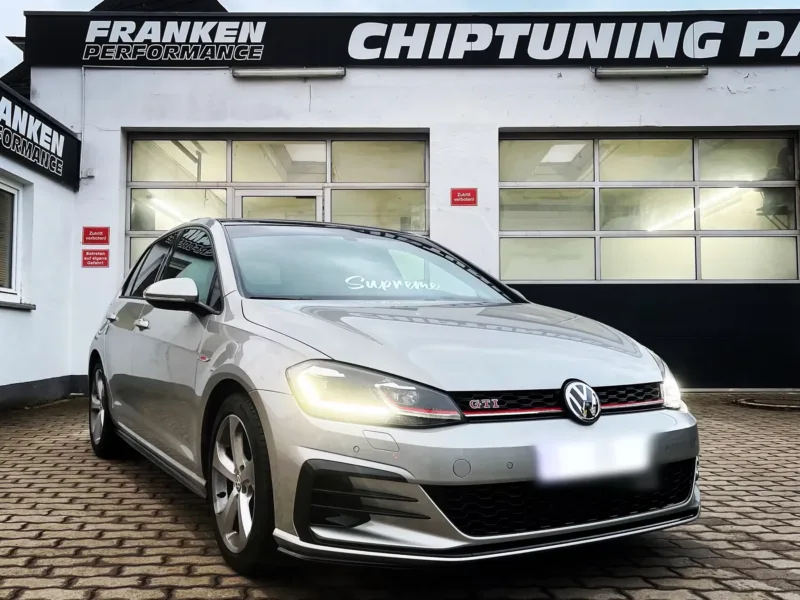 Silberner VW Golf 7 GTI mit eingeschalteten Scheinwerfern vor der Werkstatt von Franken Performance