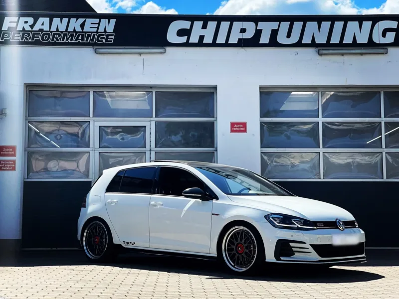 Weißer VW Golf 7 GTI mit TCR-Schriftzug und Kreuzspeichenfelgen vor der Werkstatt von Franken Performance